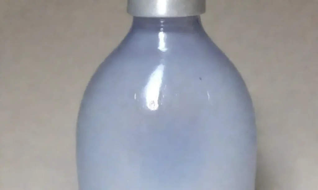 Fondo suave y etéreo con una botella de aceite de almendra centrada y elementos que sugieren frescura y calma